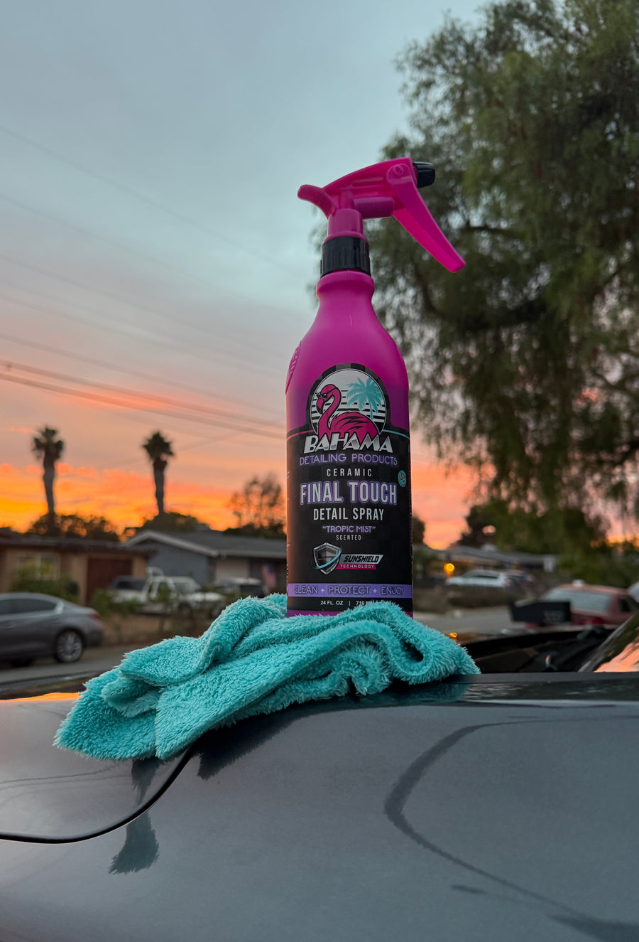 Bahama Ceramic Final Touch Detail Spray on a freshly detailed hood at sunset, microfibre towel beside it, palm trees and orange sky behind.
